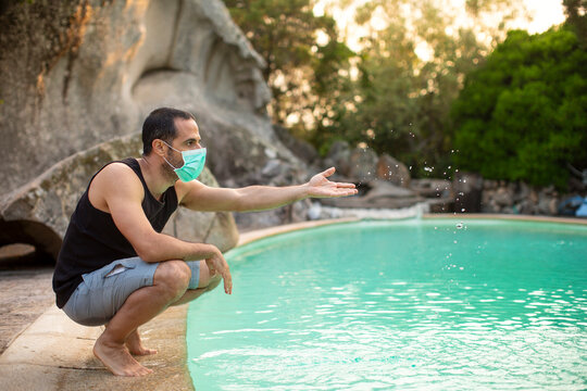 Uomo moro , con mascherina facciale gioca con l'acqua in piscina