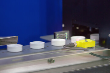 Photoelectric Sensor for Bottle cap detection in machine factory. Photo sensor installed in industrial machine.