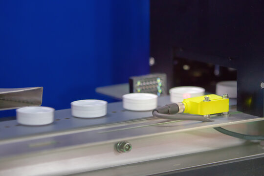 Photoelectric Sensor for Bottle cap detection in machine factory. Photo sensor installed in industrial machine.