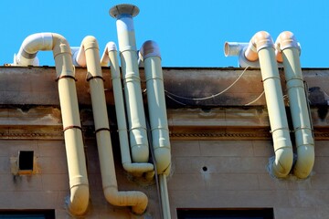 exhaust pipes of the heating fumes of an ancient building in the historic center of Palermo in Italy with a blue sky in the background