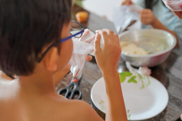 Kids baking and cake decorating at home. View from behind.