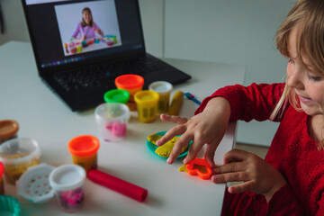 Child play with clay molding shapes during online lesson