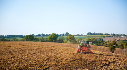 Fototapeta premium Agriculteur au volant de son tracteur dans un champ au printemps.
