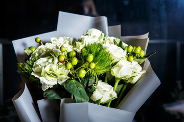 closeup elegant bouquet of big white roses and fresh greenery in gift craft paper