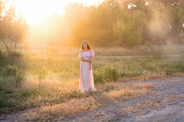 young woman walking in the park. Beautiful girl in a long dress at sunset. Summer and relaxation. Travels