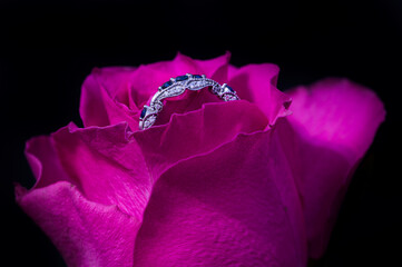 Engagement ring with blue stones in a mauve rose flower.