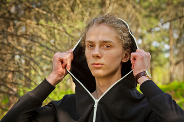 Handsome, young guy in a tracksuit plays sports in the park on the nature. Healthy lifestyle.