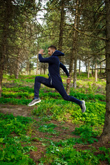 Handsome, young guy in a tracksuit plays sports in the park on the nature. Healthy lifestyle.