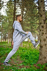 Handsome, young guy in a tracksuit plays sports in the park on the nature. Healthy lifestyle.