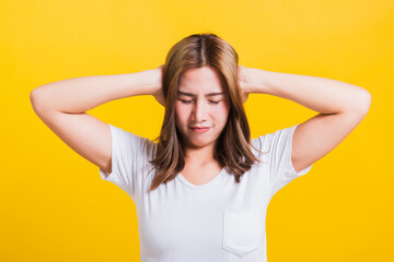 Fototapeta premium Asian Thai happy portrait beautiful cute young woman smile have closed palms ears with palms and close eyes, studio shot isolated on yellow background with copy space