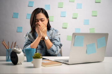 Asian woman working on a laptop was sick with fever sitting at home office. WFH. Work from home. Prevention Coronavirus COVID-19 concept.