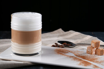 Glass Cup of coffee latte macchiato or cappuccino with foam on a dark background serving on the table
