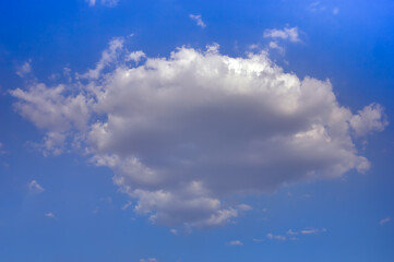 Obraz premium Lonely white cumulus cloud in a blue spring sky. Nature background.