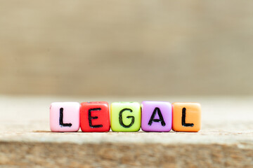 Colorful bead with black letter in word legal on wood background
