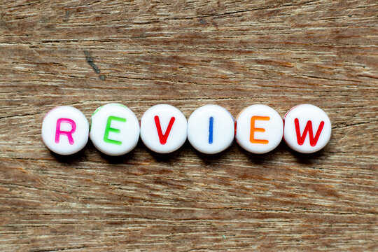 White bead with color letter in word review on wood background