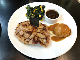 Chicken steak with mashed potatoes, corn and spinach on a black wooden table