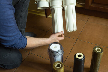 Changing filters in your home water purification system. The master installs flasks with new...