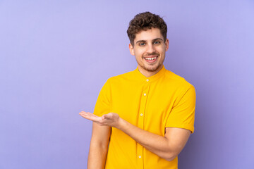 Caucasian man isolated on purple background presenting an idea while looking smiling towards