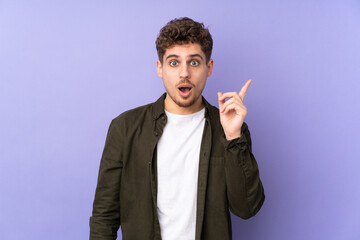 Caucasian man isolated on purple background intending to realizes the solution while lifting a finger up