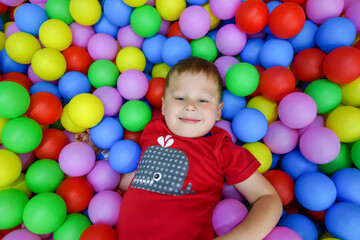 Fototapeta na wymiar the boy lies in the pool with colored balls