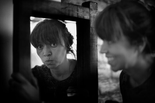 Mulher refletida no espelho, mulher sorrindo e reflexo s&eacute;rio