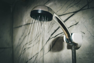 Naklejka na ściany i meble A refreshing shower with water flowing from the shower head and the modern bathroom faucet.