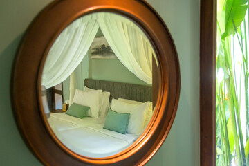 Mirror reflection of a contemporary bedroom, round mirror with simple wooden frame