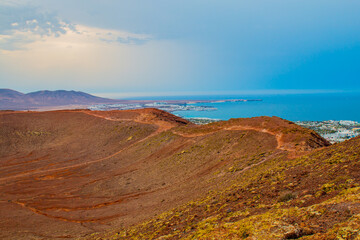 Fototapeta na wymiar panoramic view of Volcano Montana Roja de Playa Blanca, Lanzarote, Spain. One of the most popular volcano in Canary Islands and the total view of the village in the south with white houses. 