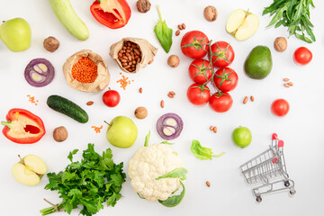 Vegan grocery set of organic vegetables, fruits and cereals on a white background with a shopping trolley. Shopping concept.