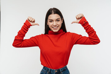 Photo of cheerful young woman smiling and pointing fingers backward