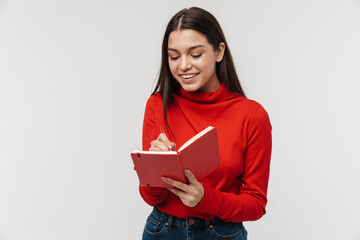 Fototapeta premium Photo of happy caucasian woman smiling and making notes in planner
