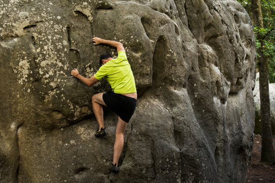 Young Man Rockclimbing /bouldering Outside On A Beautiful  Rock In A Forest In Soft Sunlight.