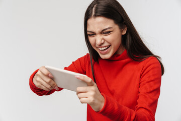 Photo of excited woman smiling while playing video game on cellphone