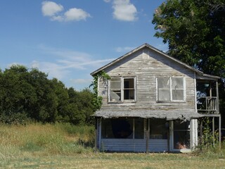 An abandoned two-storey wooden house with a balcony in the countryside