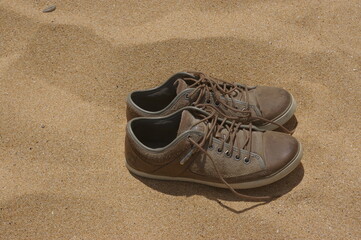 Naklejka premium A closeup of a pair of leather shoes on a beach.