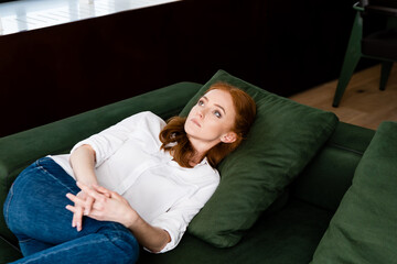 Obraz premium Selective focus of depressed woman with clenched hands lying on couch