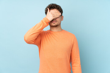 Caucasian man isolated on blue background covering eyes by hands. Do not want to see something