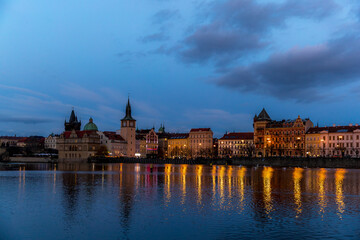 The center of Prague Czech Republic and its biggest landmark on the Vltava river Charles Bridge and the beautiful waterfront illuminated during Christmas at sunset with reflections of lights