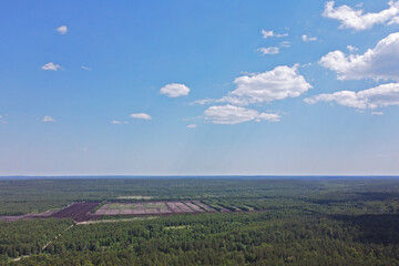 Above the site where peat is extracted the summer blue sky with white clouds