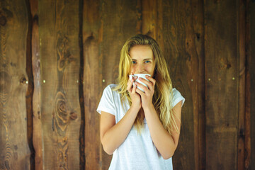 Young woman drinking coffee in front of wooden wall
