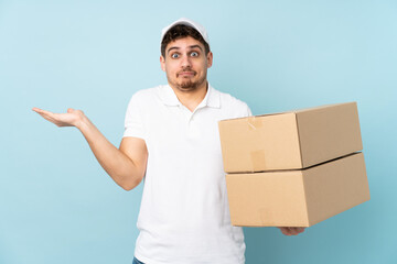 Delivery caucasian man isolated on blue background having doubts with confuse face expression