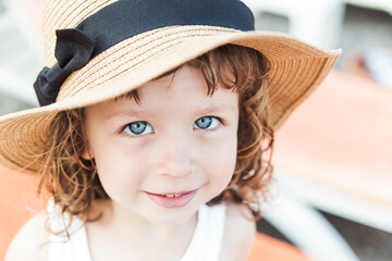 Pretty child girl with big blue eyes in hat on the beach with sea view.Vacation,summer concept