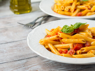 Penne pasta with fresh tomatoes and basil on wooden table. Traditional italian dish