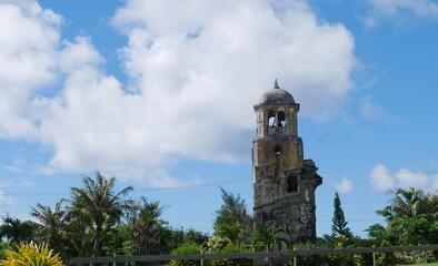 Fototapeta na wymiar Wide shot of the San Jose catholic church with the old bell tower, remnants of the old church after the World War 11 on Tinian, Northern Mariana Islands