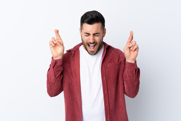 Young handsome man with beard wearing a corduroy jacket over isolated white background with fingers crossing