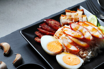 Thai dish '' Khao mu daeng '' or red sauce pork stew with rice in the black plate on the black table in the restuarant