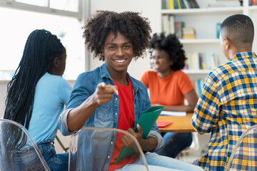 Happy african american male college student at desk at classroom
