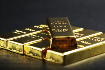 close up shot of stacked 999.9 pure gold bar ingot on a black background, represented the business,...