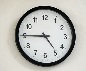 White round clock with Arabic numerals hanging on the wall
