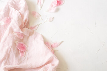 Pink fabric and peony petals on a white background